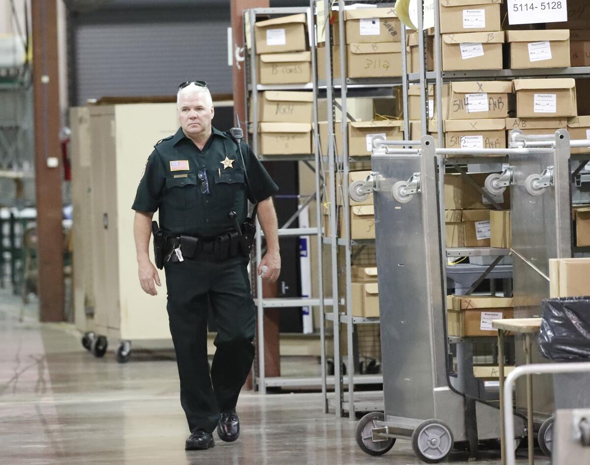 A Palm Beach County Sheriff's deputy walks past boxes of ballots before a recount on Nov. 15 in West Palm Beach, Fla.