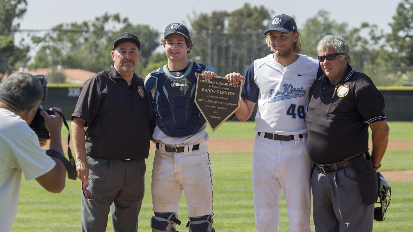 From left, base umpire Elliott Bonn, Corona del Mar High's Matt Thompson and Tom Wilcox, and head umpire Mike Little pose for a picture with a memorial home plate plaque in honor of late umpire Randy Gersten before a Pacific Coast League game against Beckman. (Kevin Chang/ Daily Pilot)