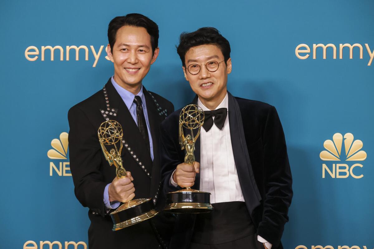 Two men in suits hold their Emmys.