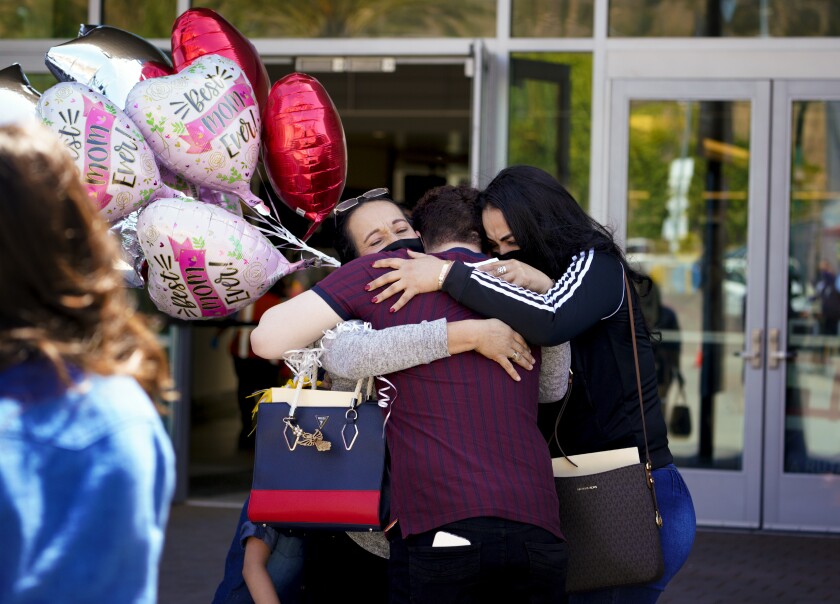 Sandra Ortiz, left hugs her son Bryan Chavez and Yeritzel Chavez at the San Ysidro Port of Entry in San Diego.