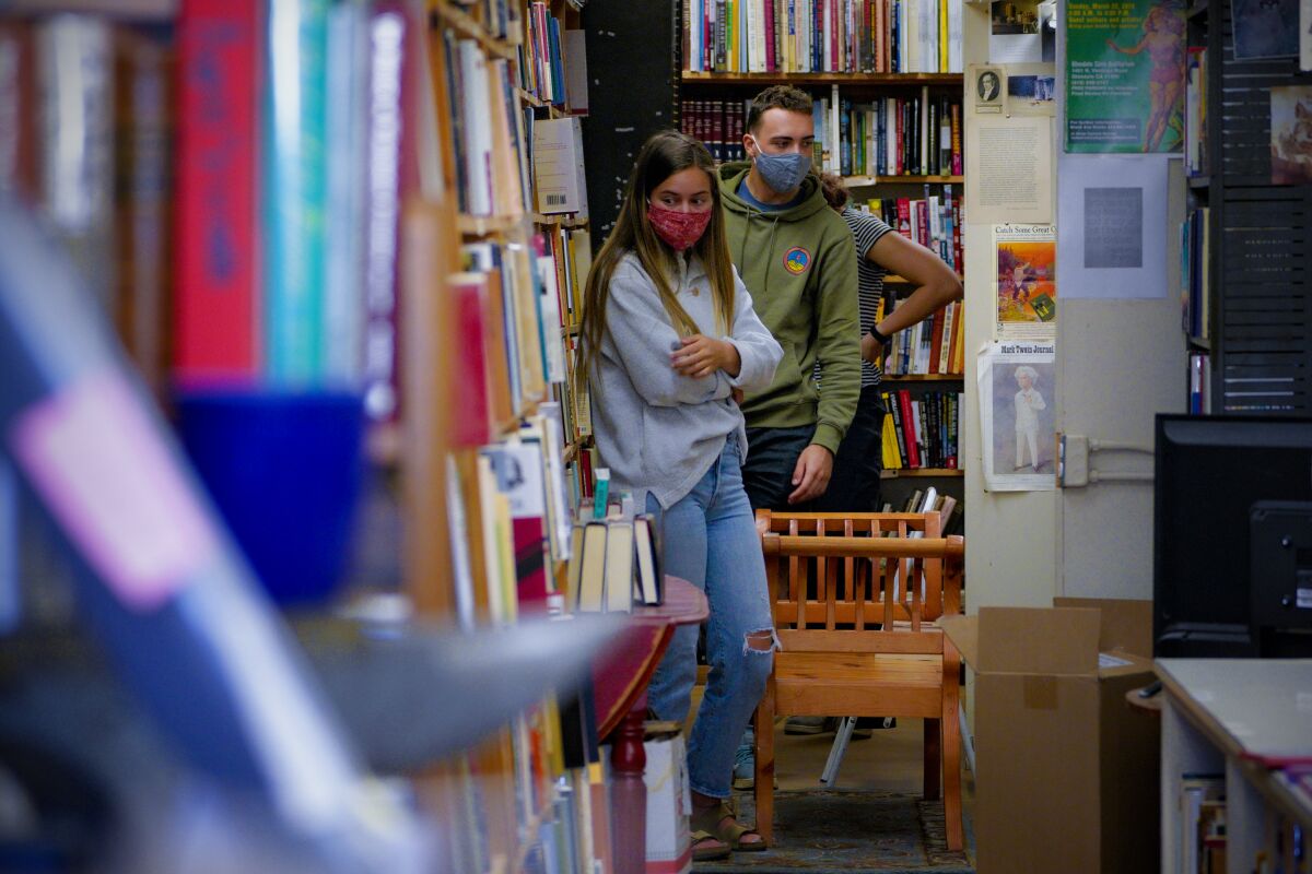 Hannah Park (left), Zander Gore and Bella Gore browse the selection of Maxwell's House of Books in La Mesa.