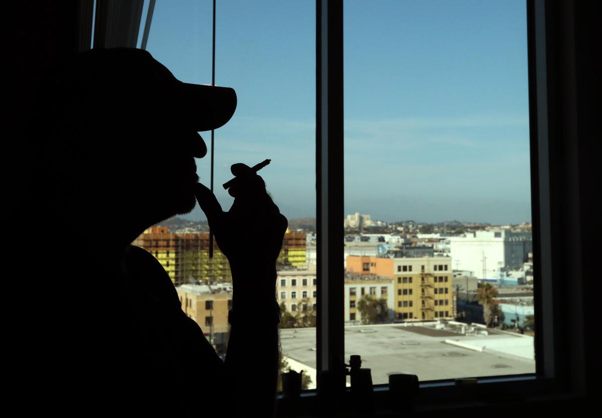 Un homme fume et regarde par la fenêtre.