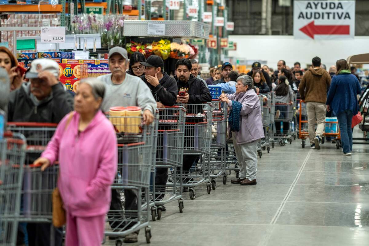 Customers buying mostly toilet paper, cleaning wipes and bottled water, queue to pay at a wholesale store in the face of the global COVID-19 coronavirus pandemic in Tijuana on Friday.