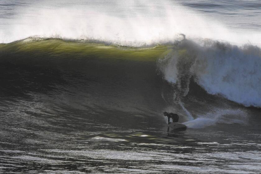 A surfer rides a big wave at Lunada Bay, where a local group called the Bay Boys keeps away outsiders.