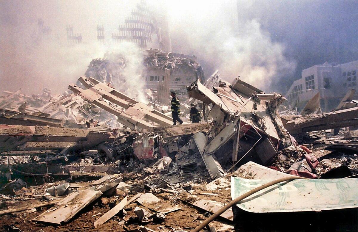 Firefighters walk amid the smouldering rubble of the World Trade Center 