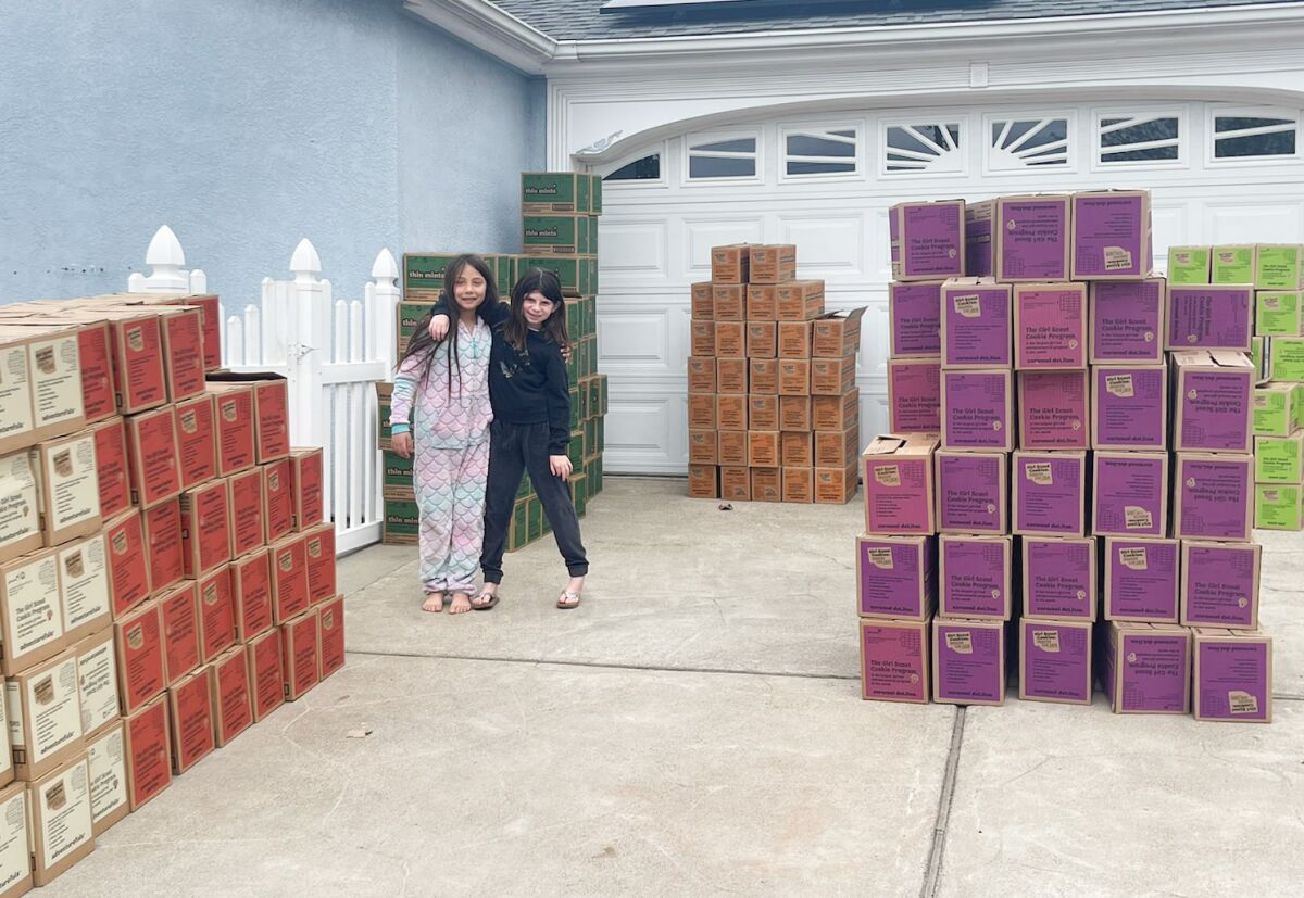 Girl Scouts Addison Barry, right, 9, and Mia Tejeda, 10, pose next to stacks of cookies.