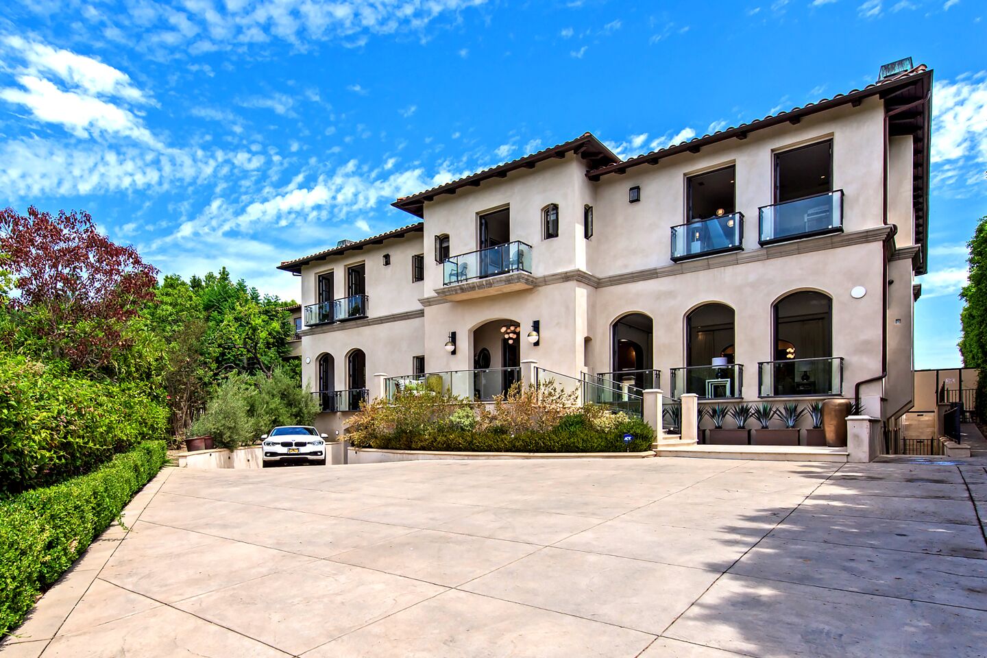 A gated driveway approaches the 13,300-square-foot home lined with oval windows and wrought-iron accents. The eight-bedroom, 12-bathroom home opens to a 25,000-gallon pool surrounded by a pavilion, lounge and lawn.