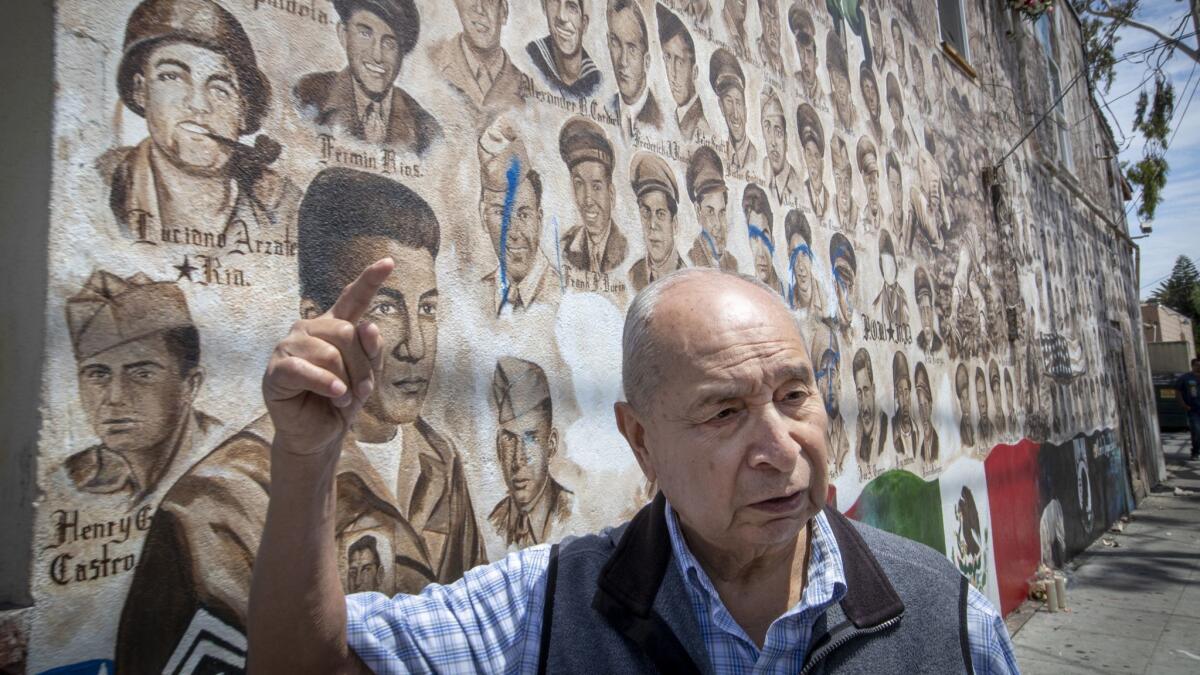 Samuel Romero, 83, a Logan neighborhood resident and veteran, speaks about vandalism near his father's portrait on a veterans' memorial that depicts portraits of 200 Mexican American men and women who have served in wars dating to World War I.