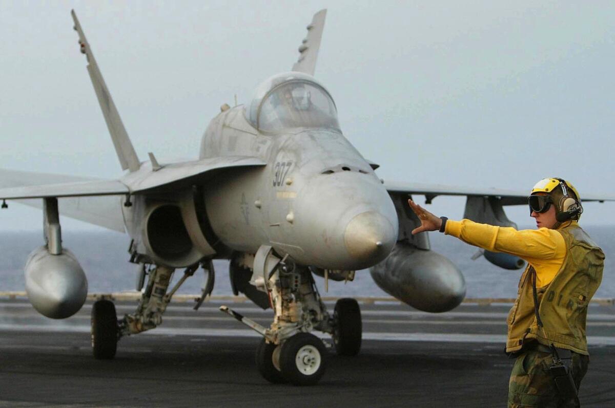 A deck crew member of the Carl Vinson guides an F/A-18C Hornet. The carrier is now in the Persian Gulf to launch airstrikes against Islamic State targets in Iraq and Syria.