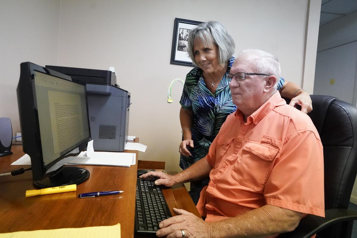 Roger West, right, columnist of the Westside Journal in northeast Florida, looks over news copy with his wife Dawn, owner and publisher, in the newspaper office Tuesday, Aug. 10, 2021, in Callahan, Fla. Outspoken as he had been in opposing COVID-19 vaccines he reconsidered after the virus returned with a deadly vengeance in mid-July. (AP Photo/John Raoux)