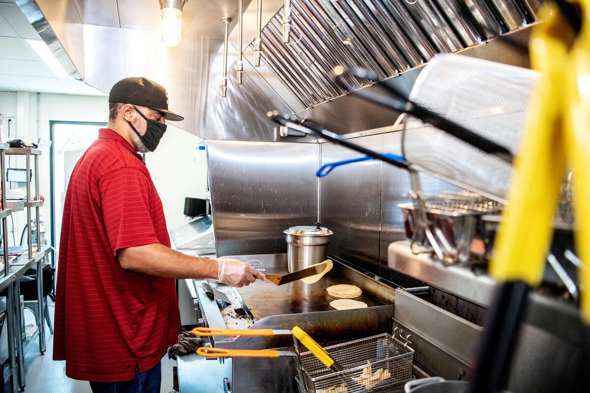 Charles Jones prepares a customer's order inside the kitchen of Taco Pete at the Grand Food Depot.