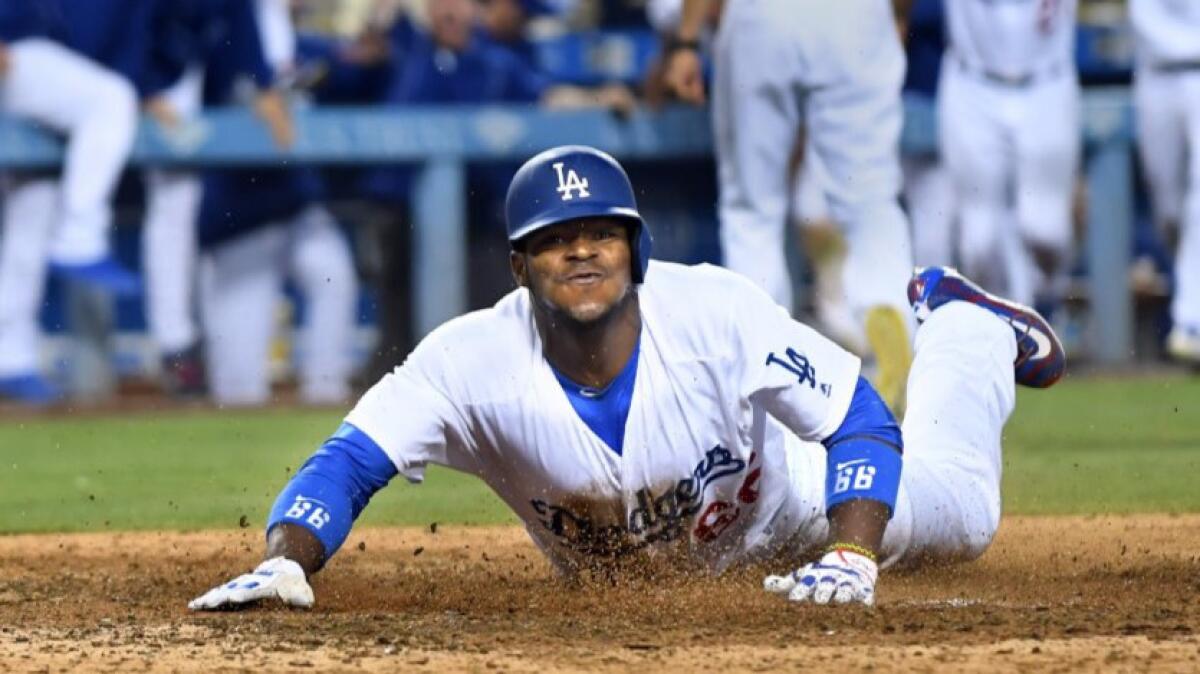 Dodgers outfielder Yasiel Puig dives in to home plate to score the winning run against the Nationals on June 22.