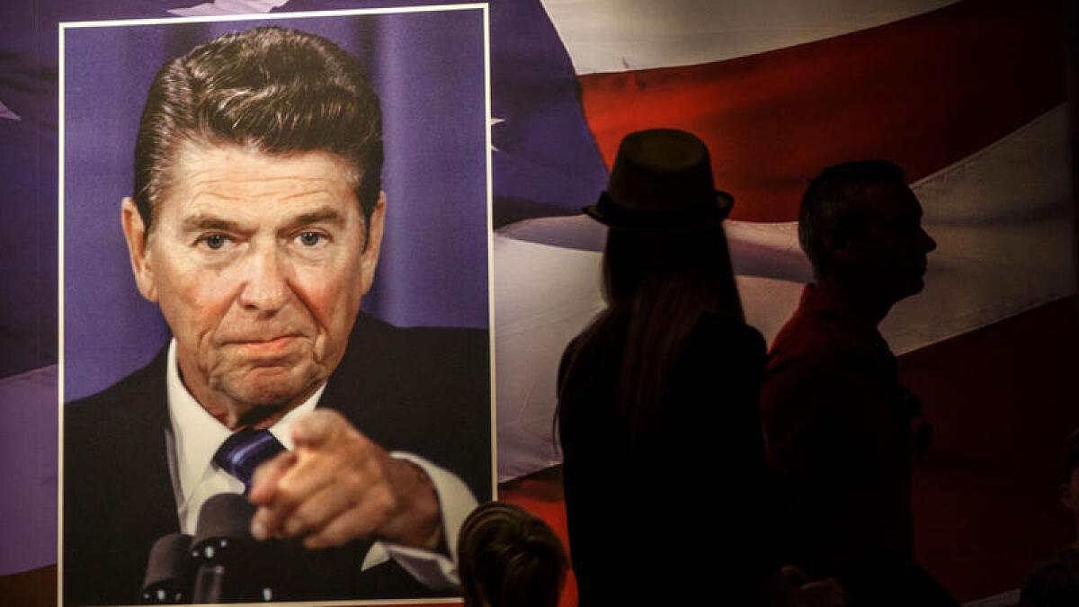 El 16 de febrero, las siluetas de los visitantes se dibujan contra una imagen de la bandera de Estados Unidos y del ex presidente Ronald Reagan, en la biblioteca presidencial Ronald Reagan.