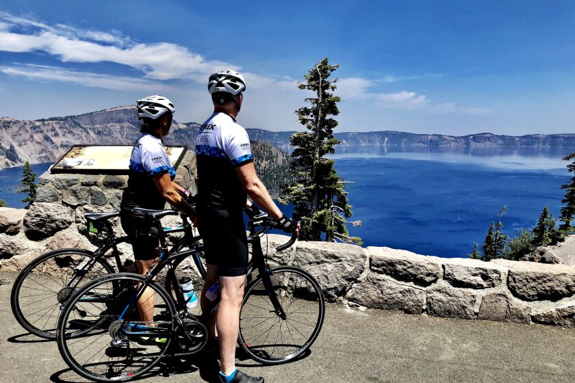 OREGON-- A pair of cyclists on a Trek Travel trip gaze out over nearly 2,000-foot-deep Crater Lake from the Rim Road, which did not open until mid-July this year because of heavy winter snows.