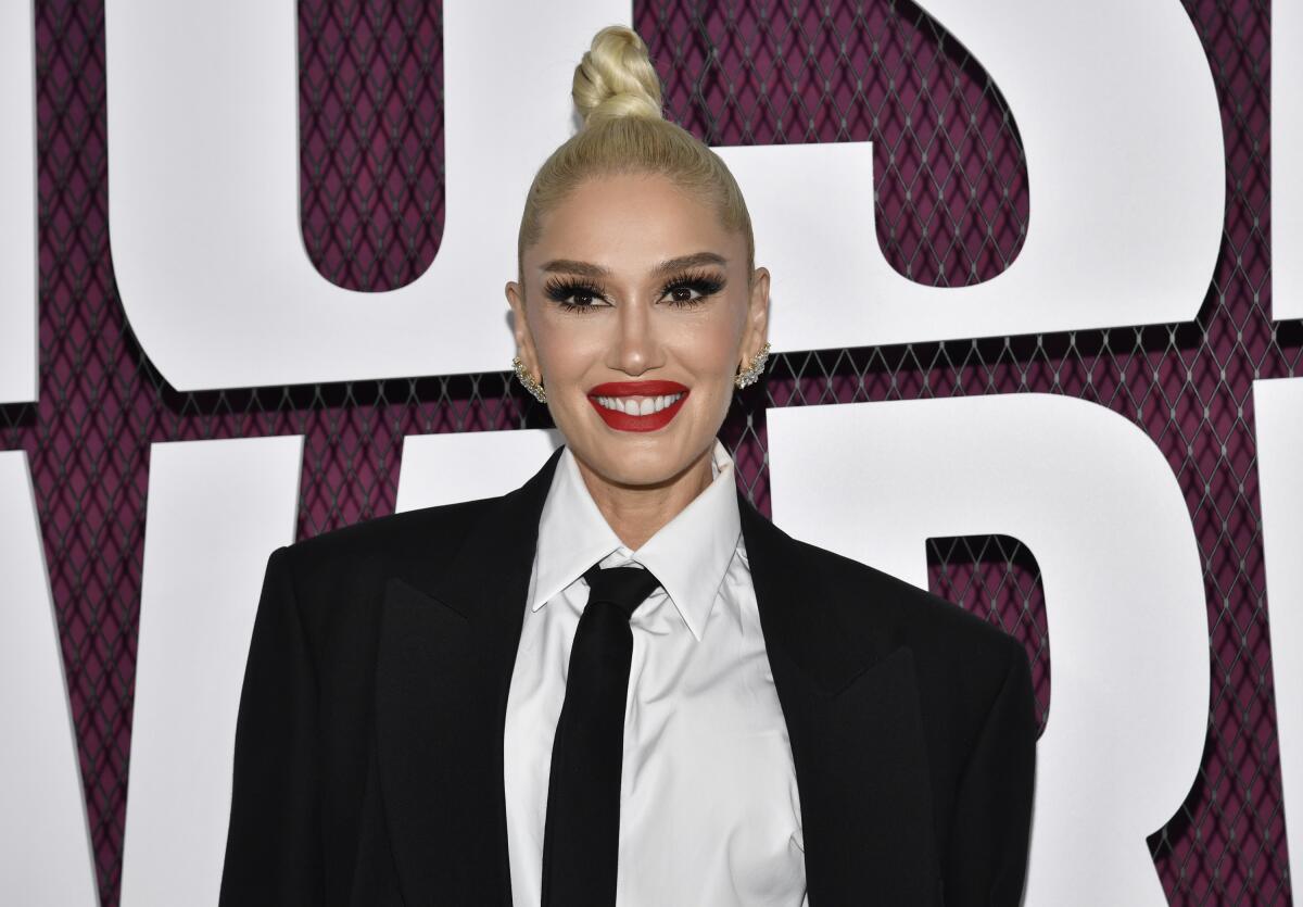 Gwen Stefani wears a black suit jacket, white shirt and black tie with her hair in a high, slicked-back bun