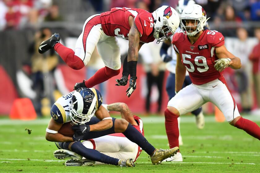 Rams wide receiver Robert Woods makes a reception as Cardinals safety Budda Baker leaps over him in front of linebacker Joe Walker.