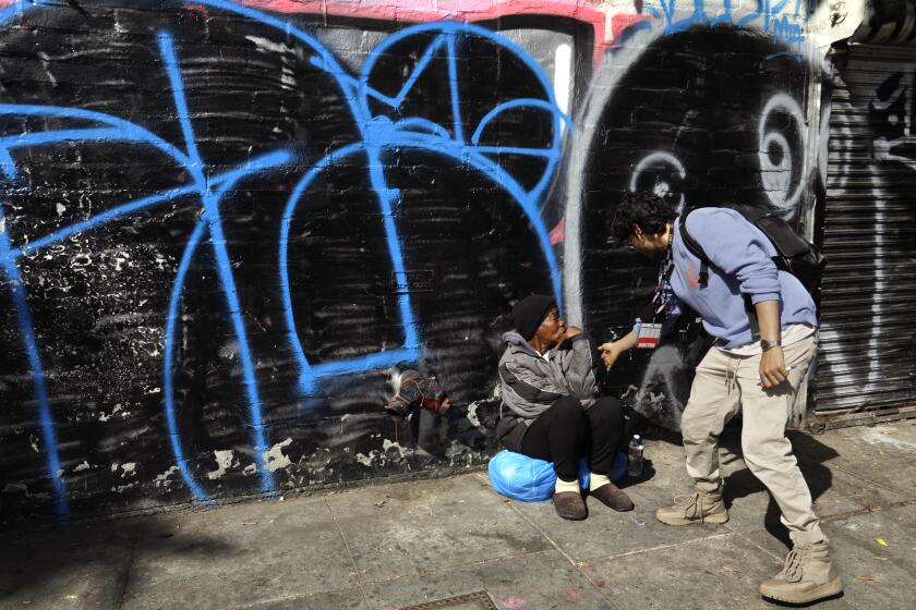 LOS ANGELES, CA - MAY 31, 2022 - - Dr. Shayan Rab, a street psychiatrist with the Los Angeles County Dept. of Mental Health, checks on a homeless woman in skid row in Los Angeles on May 31, 2022. Dr. Rab, who leads the Homeless Outreach & Mobile Engagement (HOME) team helps find mentally ill homeless to treat and tries to get them into housing. (Genaro Molina / Los Angeles Times)