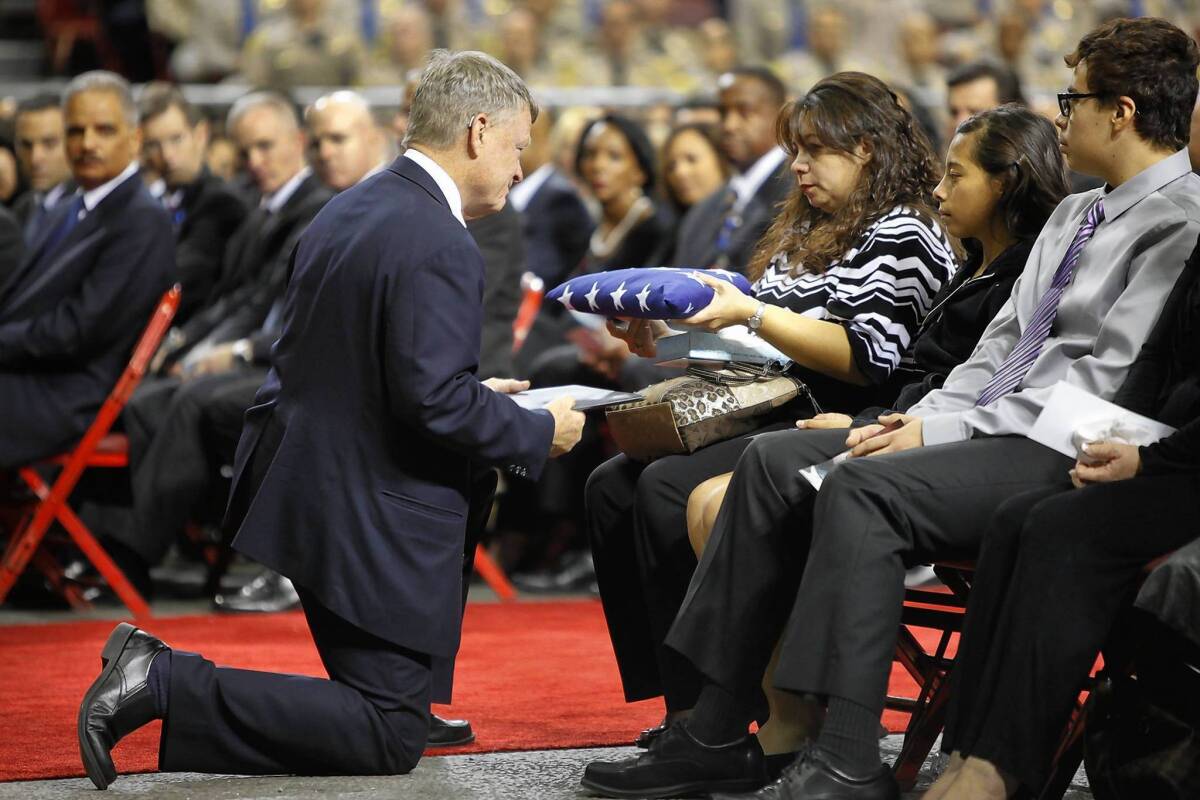 Ana Hernandez, widow of slain Agent Gerardo Hernandez, accepts a folded American flag from TSA Administrator Rand Beers at a memorial for her husband Tuesday. With her are her children, Stephanie and Luis. Gerardo Hernandez is the first TSA officer to die in the line of duty in the agency's history.