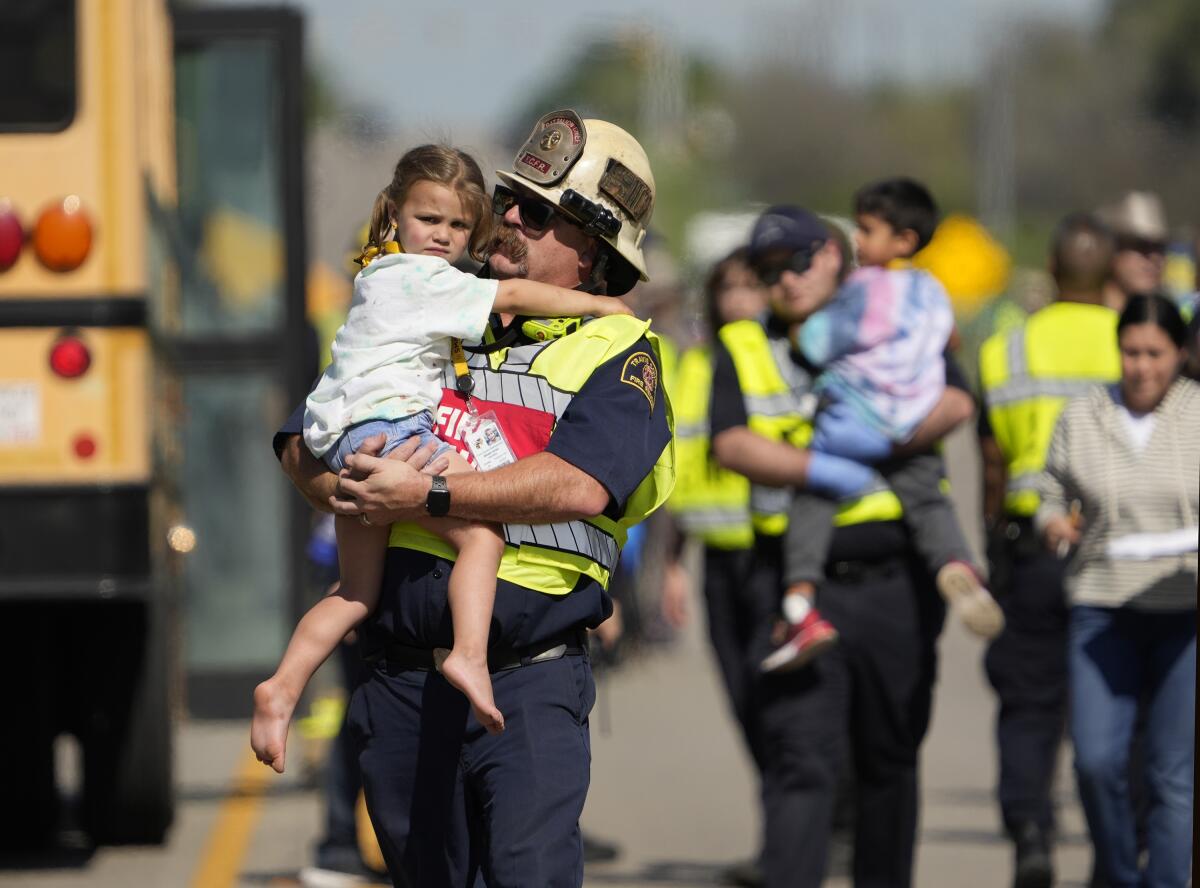 Emergency workers carry children in their arms away from a school bus crash.