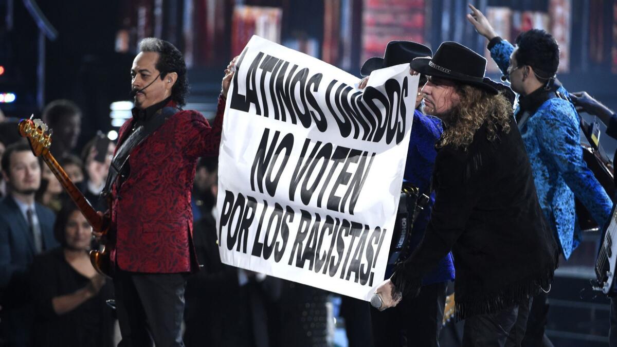 Members of Los Tigres del Norte and the rock band Maná hold up a sign that reads "Latinos United. Don't Vote For Racists" at the 2015 Latin Grammy Awards.