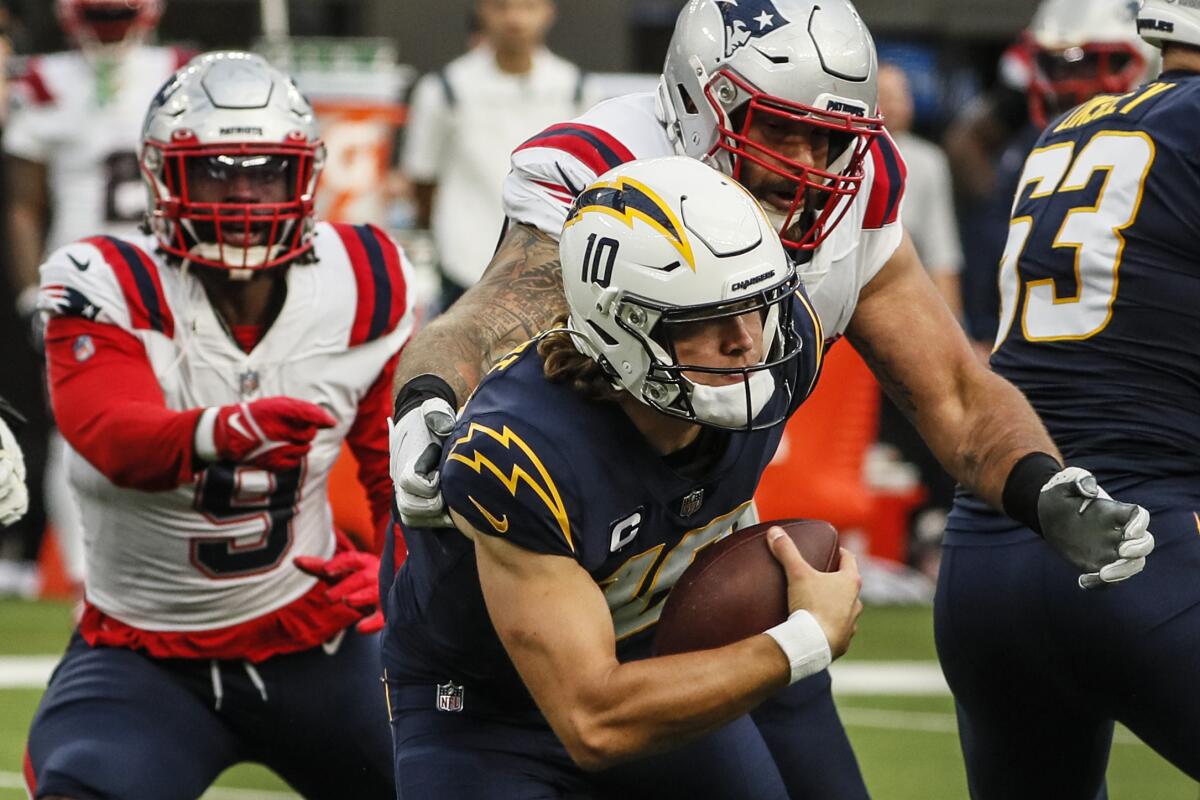 Patriots defenders pursue and sack scrambling Chargers quarterback Justin Herbert.