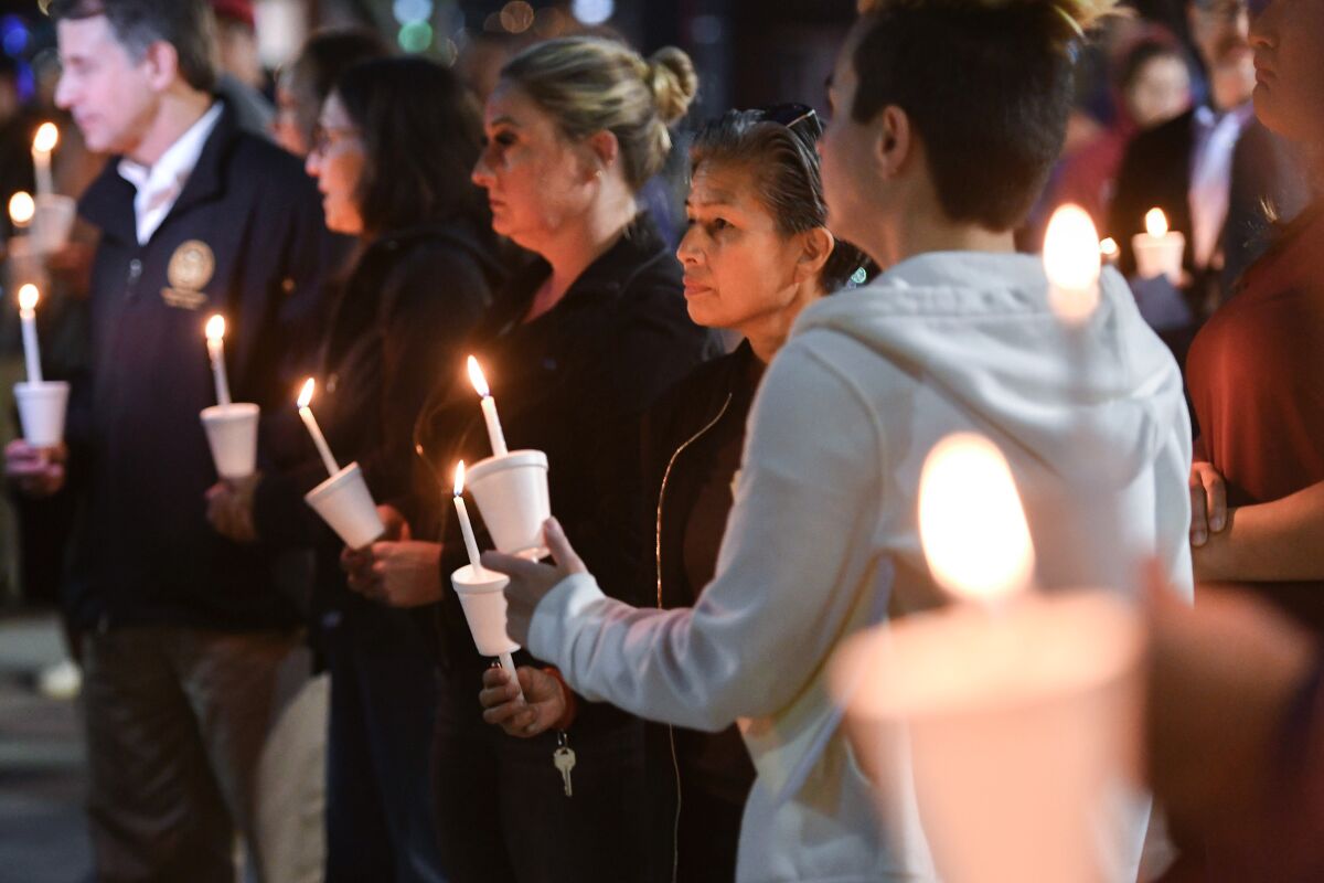 People hold candles at a vigil.