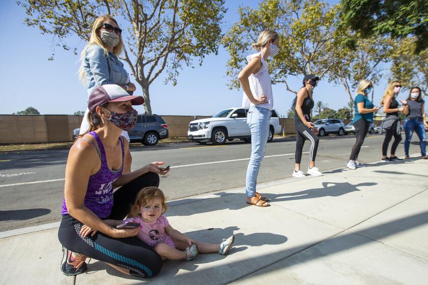 Rebecca Peranio, left, with her daugther Serafina, aloing with other parents, wait for their children following the first day of in-person school at Mariners Elementary School on Tuesday, Septemer 29