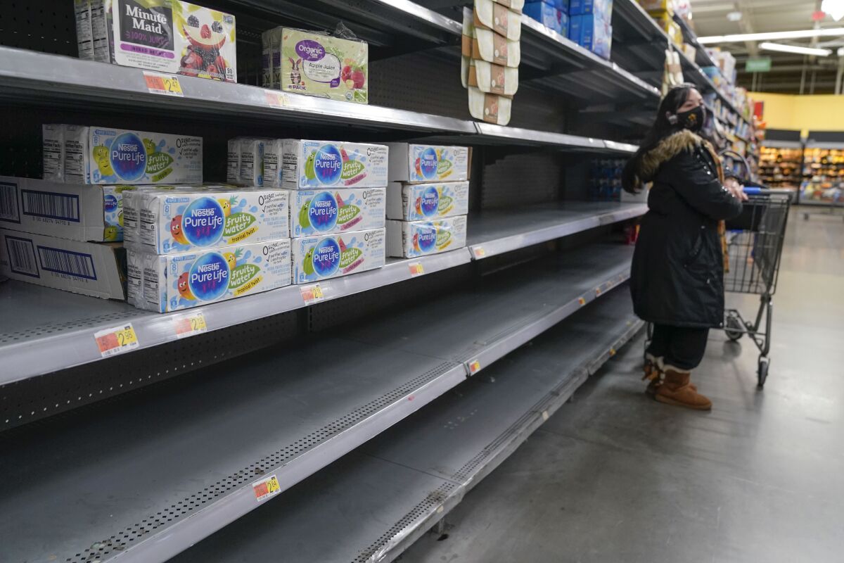 FILE - A woman looks over shelves, some of which are empty, at a Walmart store in Teterboro, N.J., on Jan. 12, 2022. The Justice Department is launching a new initiative aimed at identifying companies that exploit supply chain disruptions in the U.S. to make increased profits in violation of federal antitrust laws. (AP Photo/Seth Wenig, File)