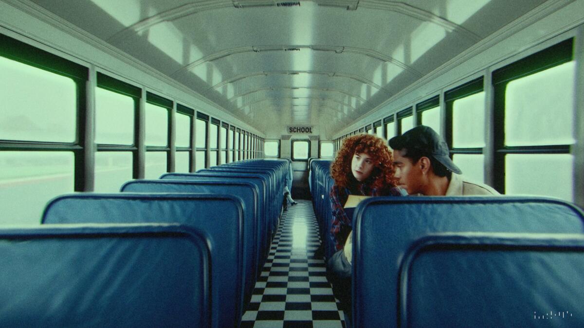 Two people in an otherwise empty bus with blue seats and a checkerboard floor