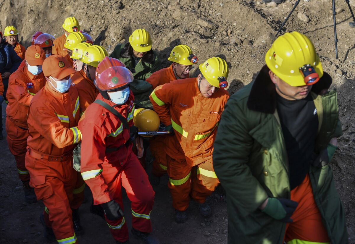 In this photo released by China's Xinhua News Agency, rescuers evacuate a trapped miner from a flooded coal mine in Xiaoyi city in northwestern China's Shanxi Province, Friday, Dec. 17, 2021. Crews have safely rescued 20 of 21 Chinese coal miners trapped inside a flooded shaft, with one still missing. (Cao Yang/Xinhua via AP)