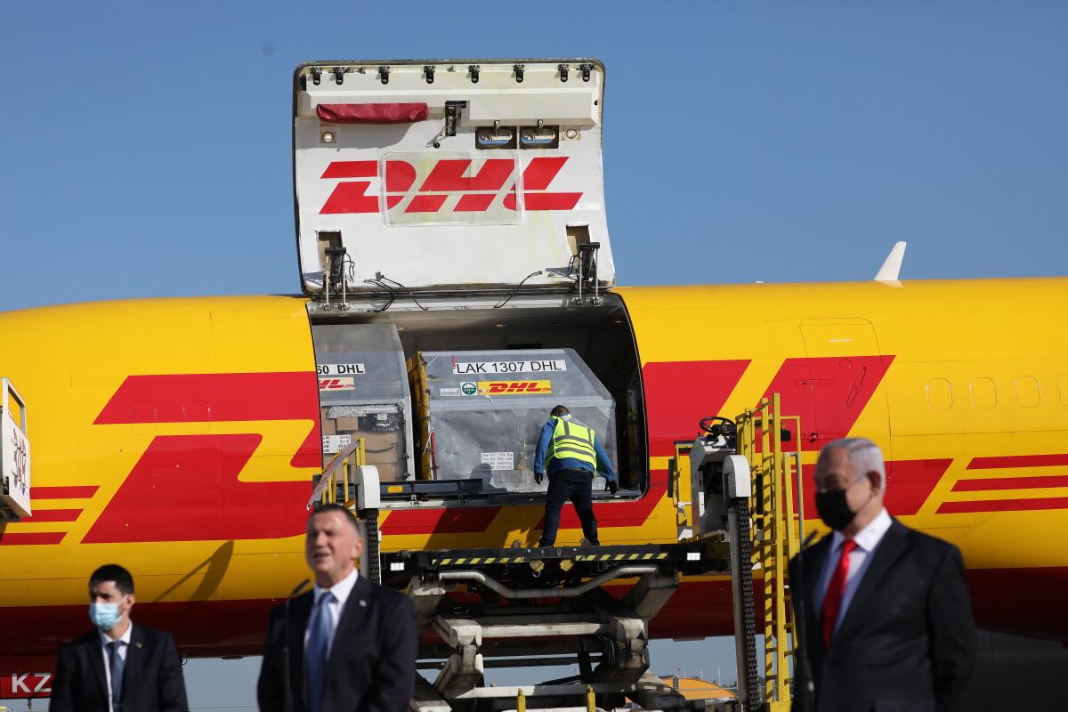 Benjamin Netanyahu stands with other men in front of a cargo jetliner with the DHL logo.