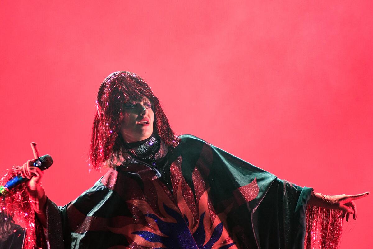 A female rock singer in a cape performs onstage