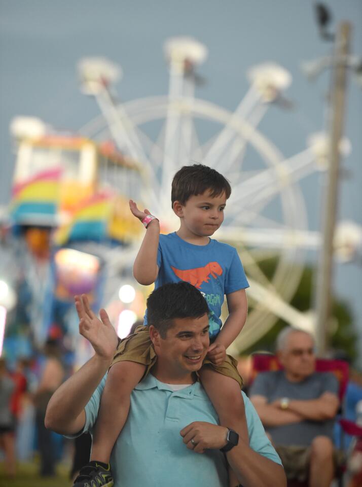 Chris Swedberg of Manchester and his 4-year-old son Jacob wave at the passing vehicles while watching the parade leading to the Manchester Volunteer Fire Company carnvial on Tuesday, July 2.