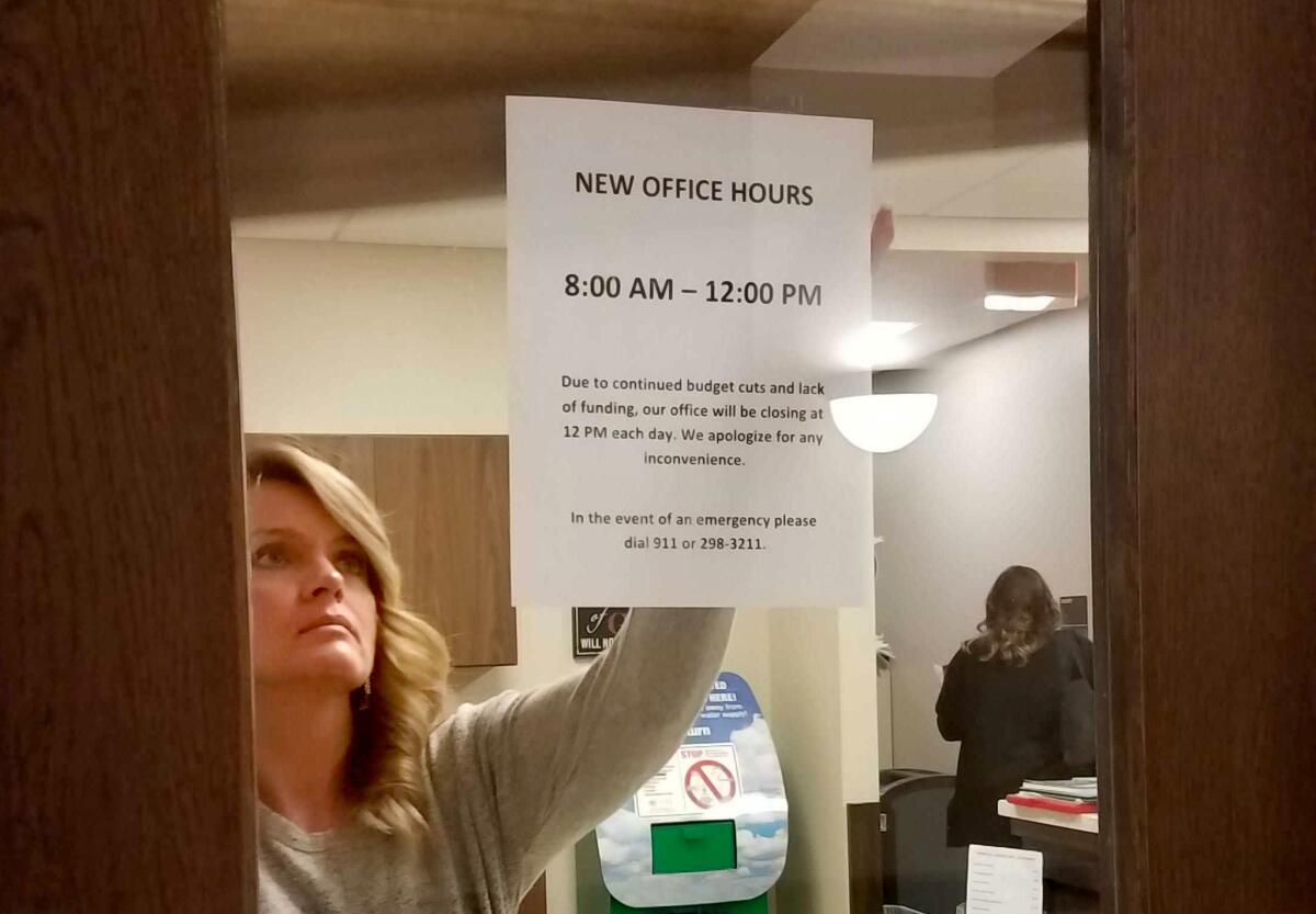 Teresa Burke, the office manager at the Martin County Sheriff's Office, lowers a blind over the front door at noon on a recent weekday.