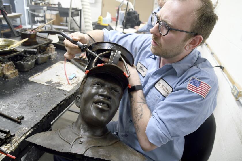 David Hobbs, an employee at Art Castings of Colorado, touches up a wax mold of Jackie Robinson's head in Loveland, Colo. on Wednesday, May 8, 2024. The original statue was cut off at the ankles and stolen from a park in Wichita, Kansas in January. The Colorado foundry cast that sculpture in 2019 and, luckily, still had the original plaster and rubber molds. (AP Photo/Thomas Peipert)