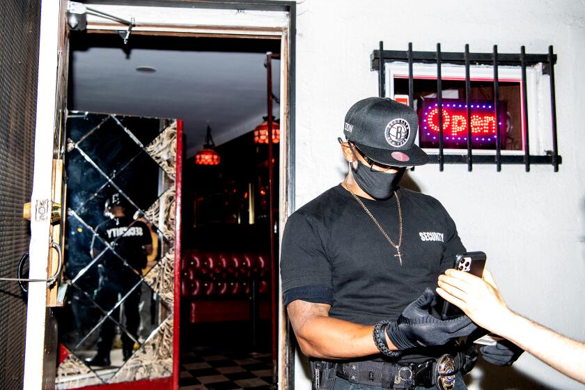 LOS ANGELES, CA - JULY 30: Security officer Don McClaren checks for proof of vaccination status from customers before they can enter the bar inside Permanent Records Roadhouse on Friday, July 30, 2021 in Los Angeles, CA. (Mariah Tauger / Los Angeles Times)