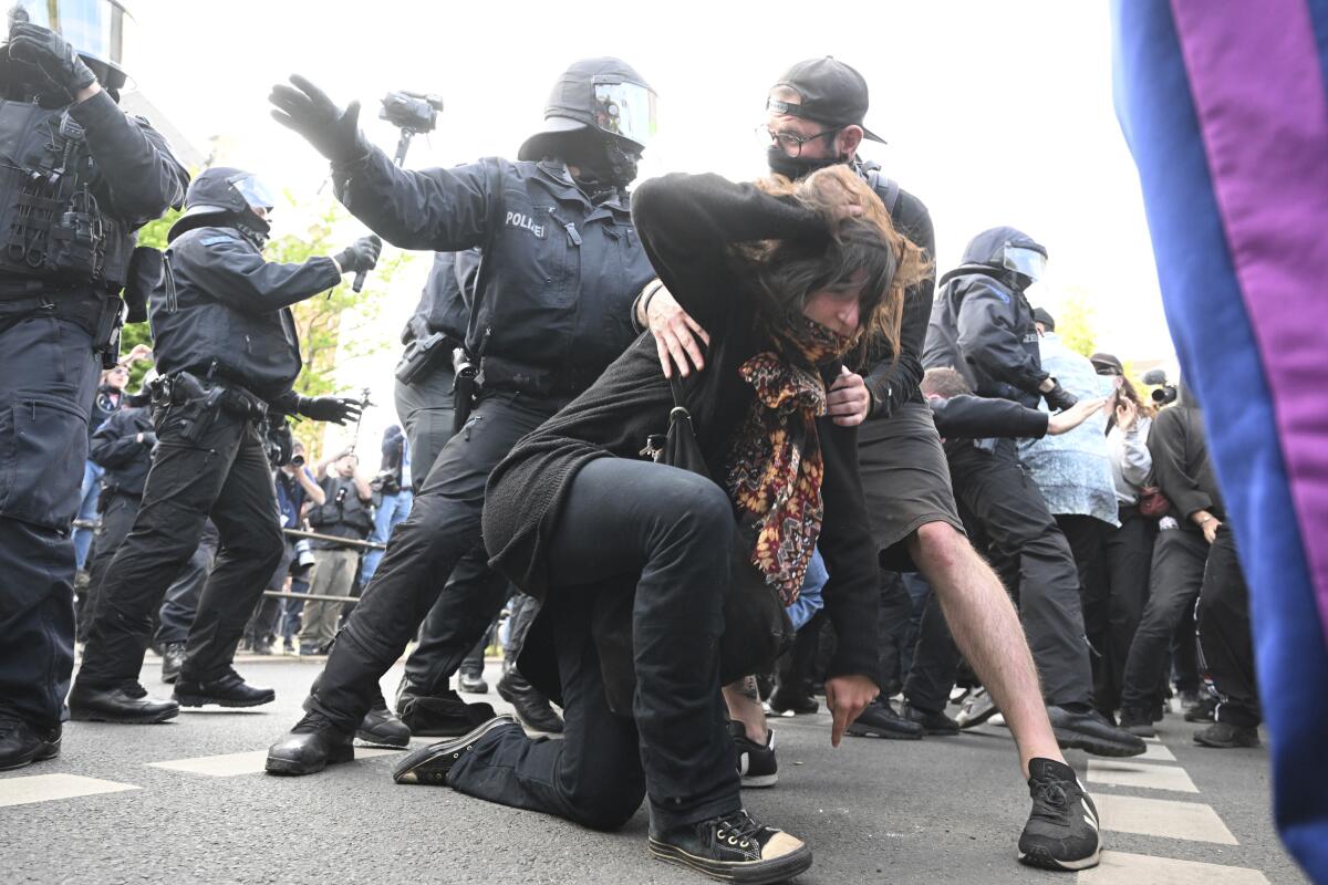 Police officers react with a woman during a left-wing demonstration, in Leipzig, Germany, Saturday, June 3, 2023. The demonstration is against the verdict in the trial of Lina E. The Dresden Higher Regional Court sentenced the student to five years and three months imprisonment. (Robert Michael/dpa via AP)