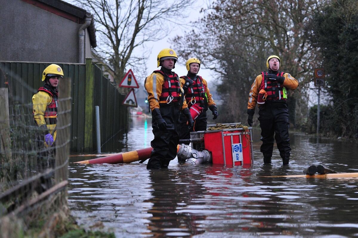 Firefighters attempt to move a pump on a flooded road near the village of Long Load in Somerset, southwest England.