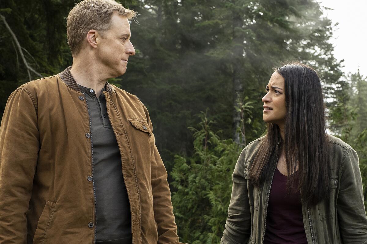 A man and a woman walk through the forest in a scene of "Alien resident."