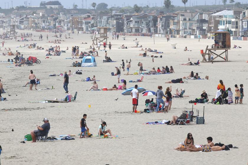 Beach-goers enjoy a warm day north of the Newport Beach pier on Thursday as Gov. Gavin Newsom announced a "hard close" of state and local beaches in Orange County beginning on Friday.