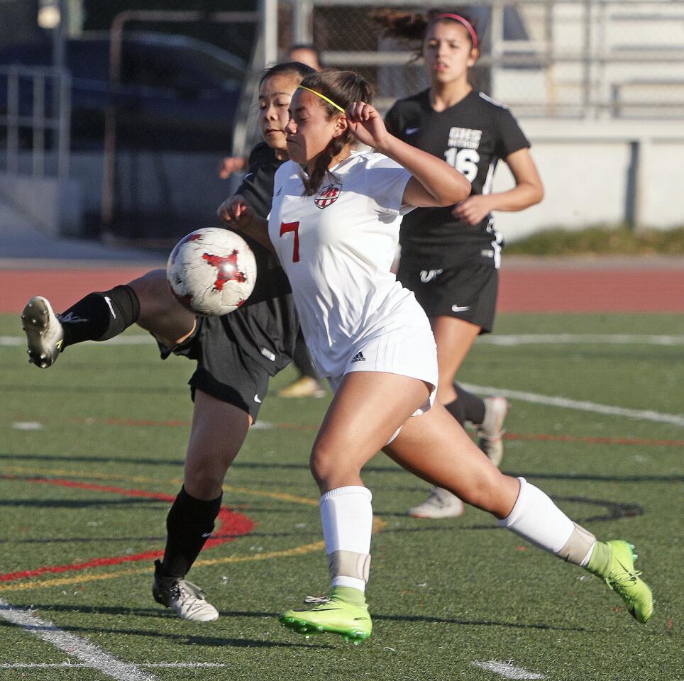 As Burroughs' Lily Gonzalez is attacking, Glendale's Rachel Fong clears the ball in a Pacific League girls' soccer game at Glendale High School on Friday, January 4, 2019.