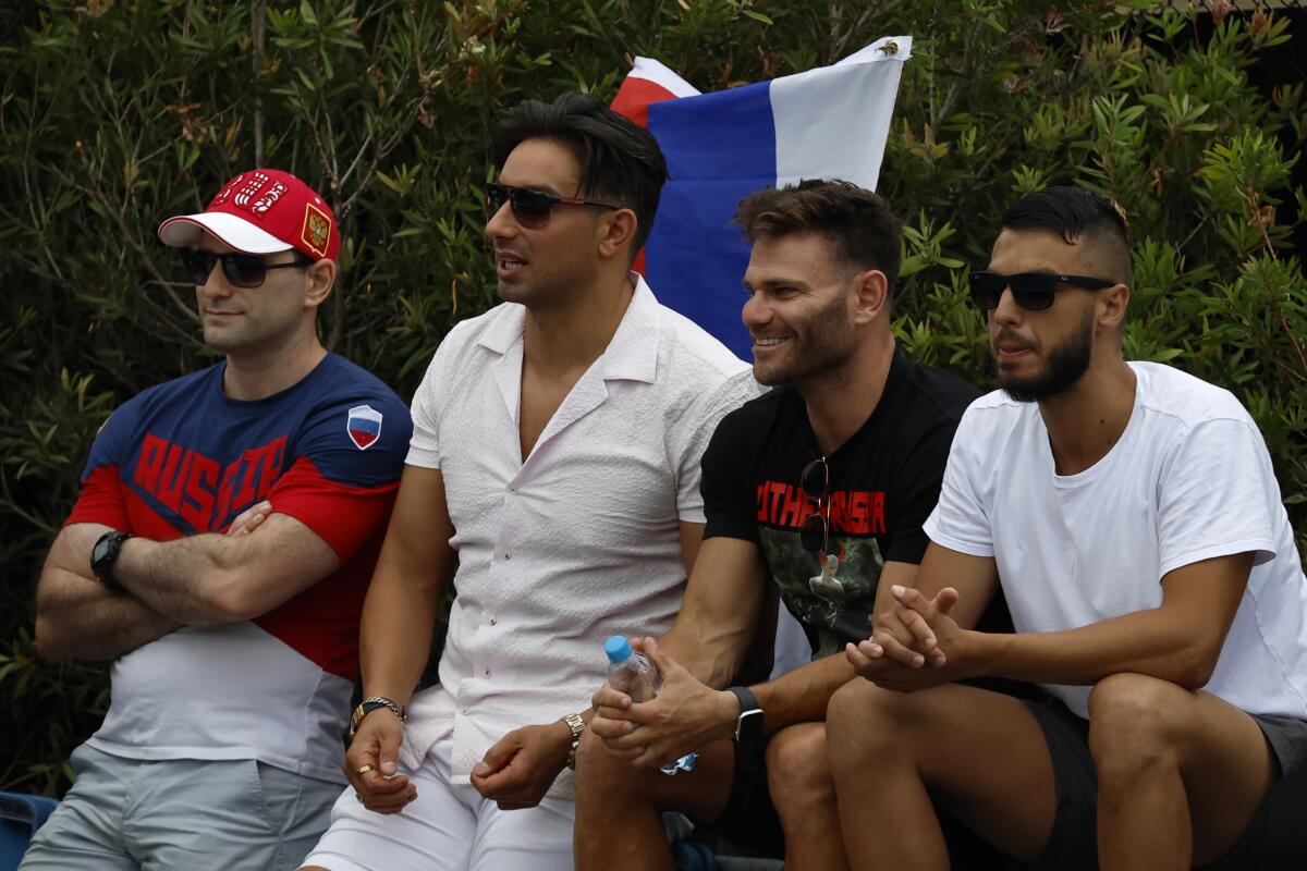 Four tennis spectators with a Russian flag behind them