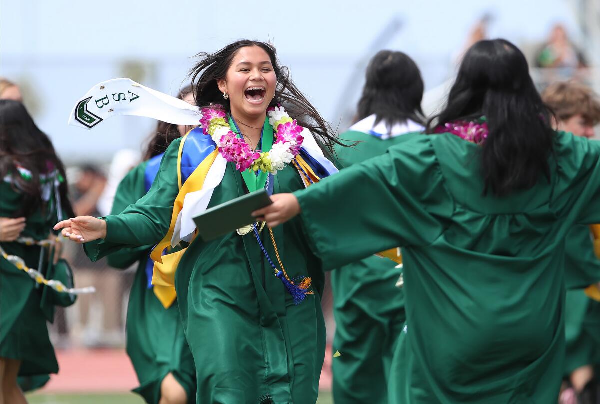 Kayla Tougas runs to embrace friends after Costa Mesa High School's commencement ceremony.