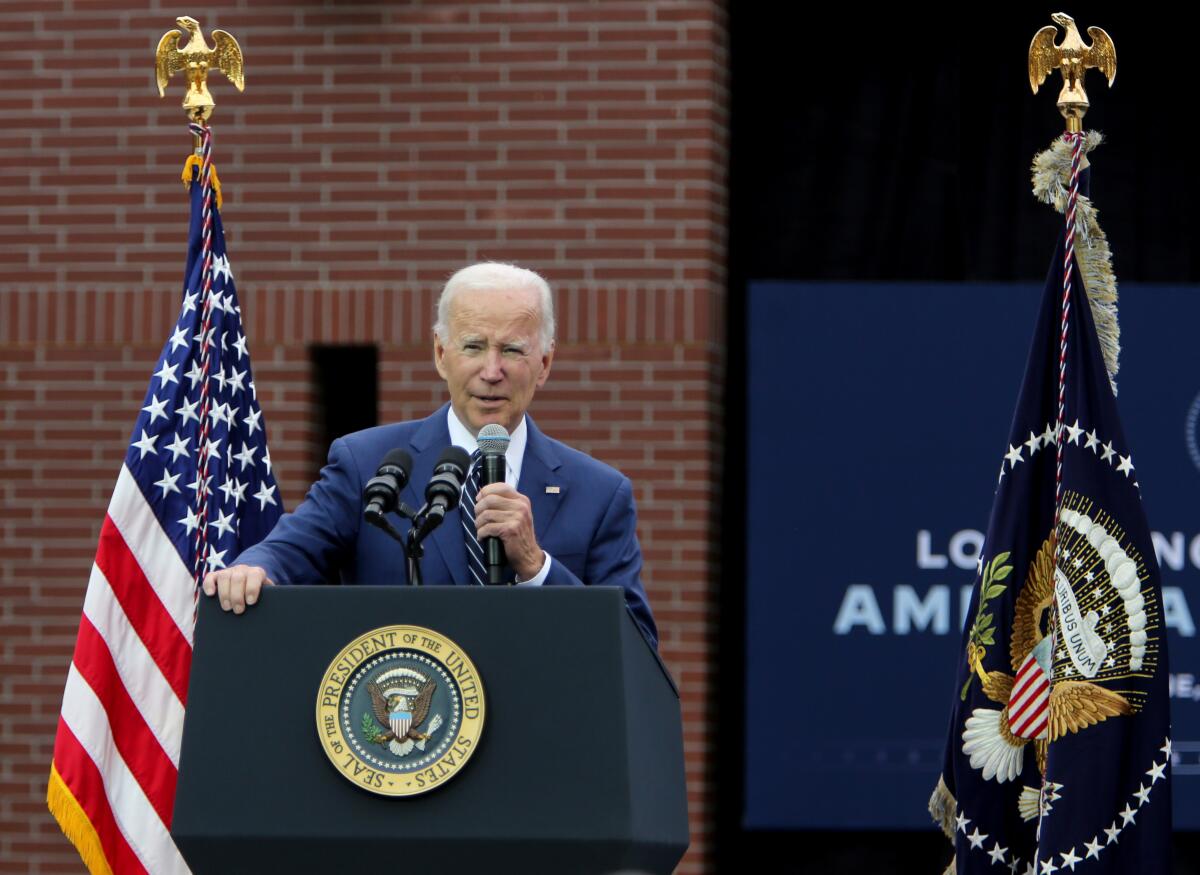 President Biden speaks from a lectern in front of a brick building