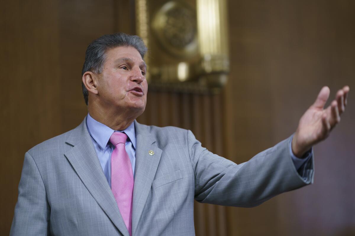 Joe Manchin reaches out with one hand as he speaks onstage.
