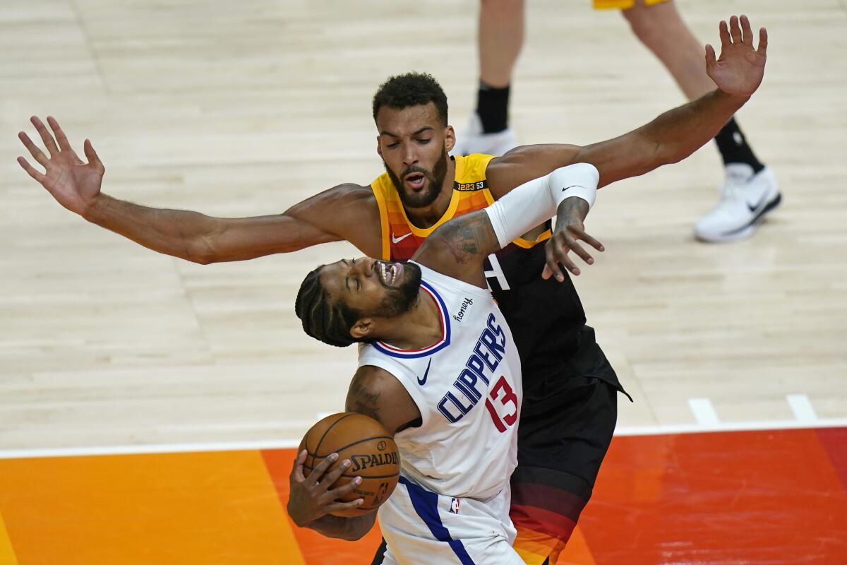 Clippers forward Paul George is knocked off balance on a drive against Jazz center Rudy Gobert.
