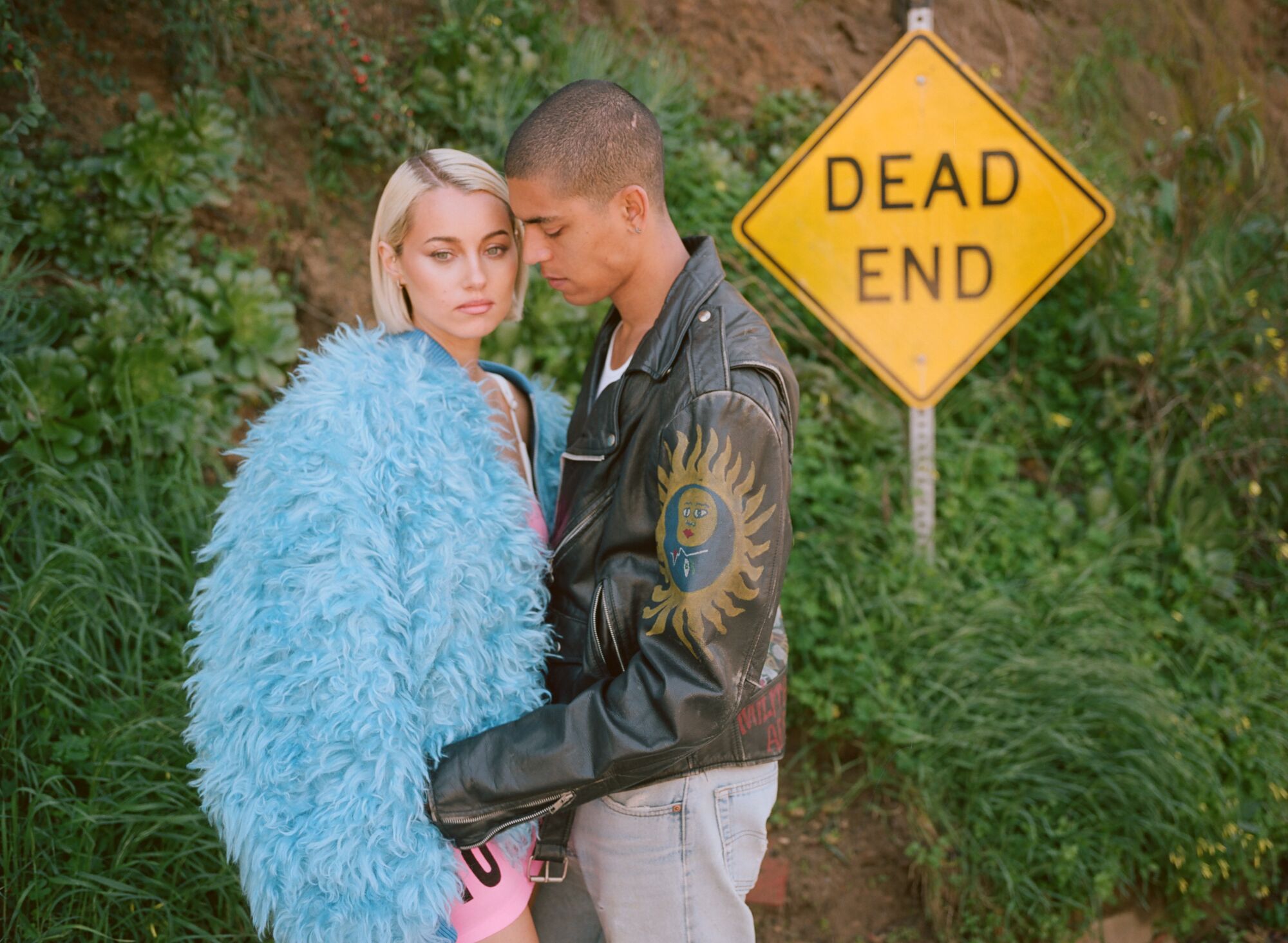 A couple embraces in front of a "Dead End" sign.
