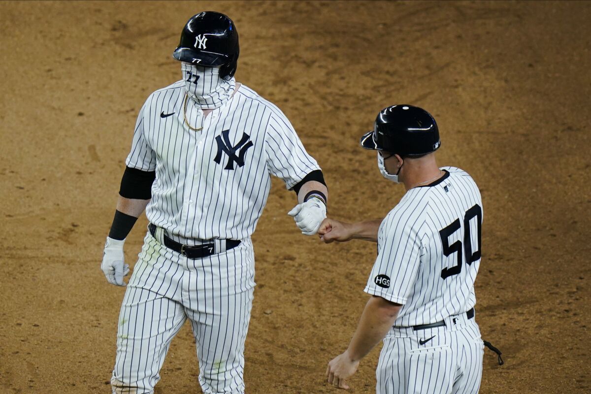 New York Yankees' Clint Frazier (77) fist bumps first base coach Reggie Willits (50) after hitting a two-run single during the seventh inning of a baseball game Saturday, Aug. 15, 2020, in New York. (AP Photo/Frank Franklin II)