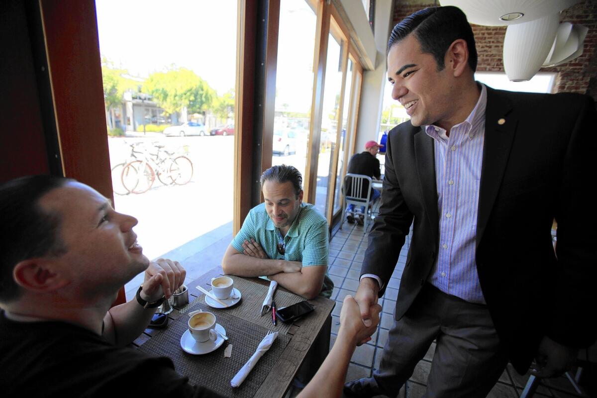 Mayor-elect Robert Garcia, right, greets Adriel Fasci at a restaurant Wednesday in Long Beach. With Fasci is Giavanni Washington. Garcia earned 52.1% of the vote.