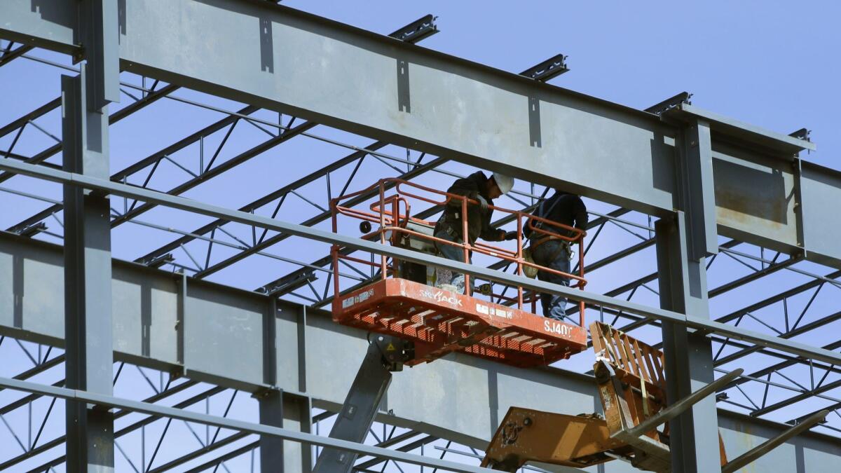 Construction workers stand in a bucket lift in Middleton, Mass.